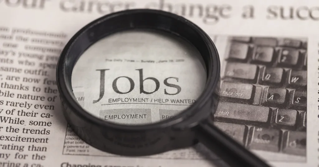 Newspaper job listings under a magnifying glass — symbolising search for local cash jobs near me NZ